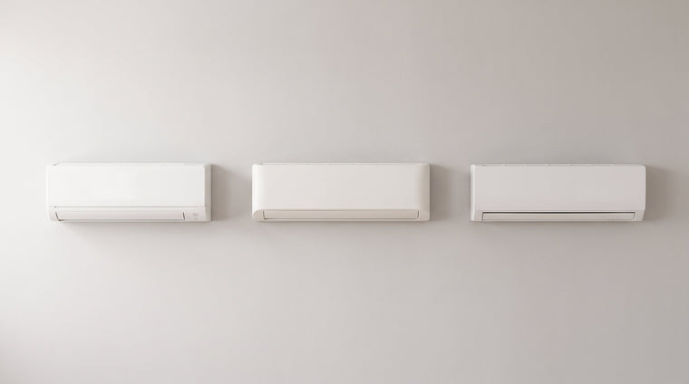 Drei weiße Split-Innengeräte unterschiedlicher Bauform nebeneinander an einer hellen Wand